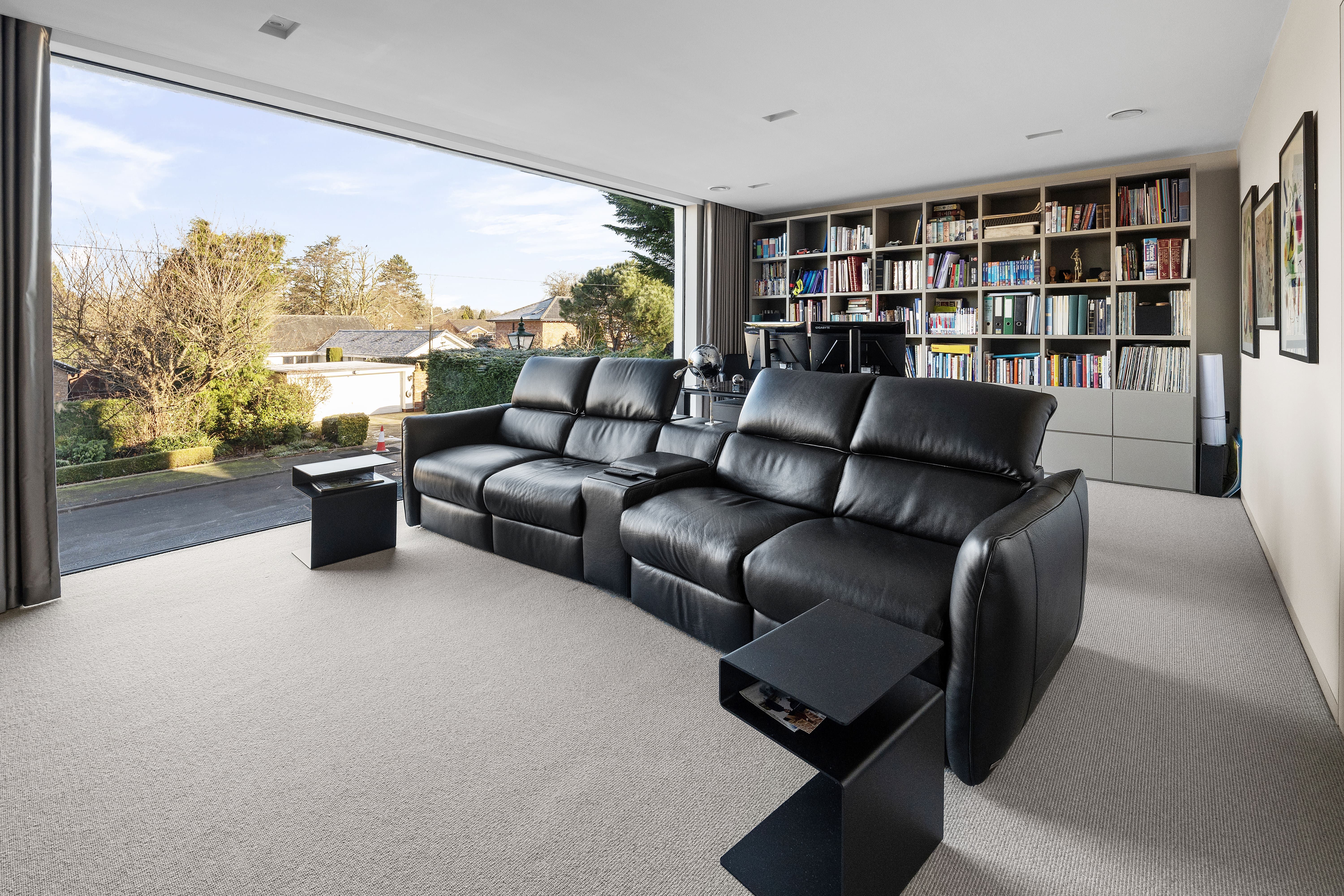 Home cinema room with leather recliner seating and a full library wall