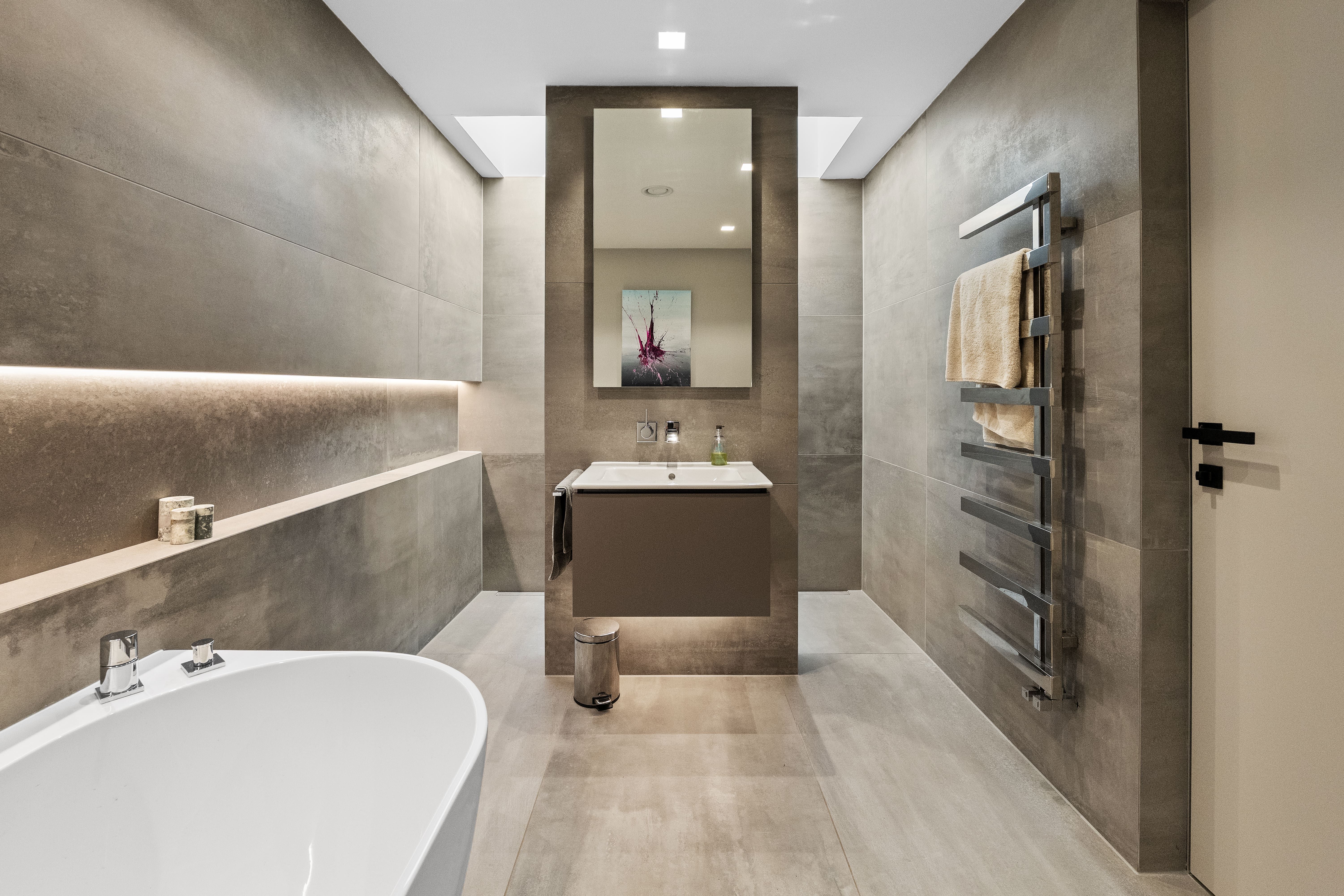 Ensuite bathroom with freestanding bath and floor-to-ceiling tiling