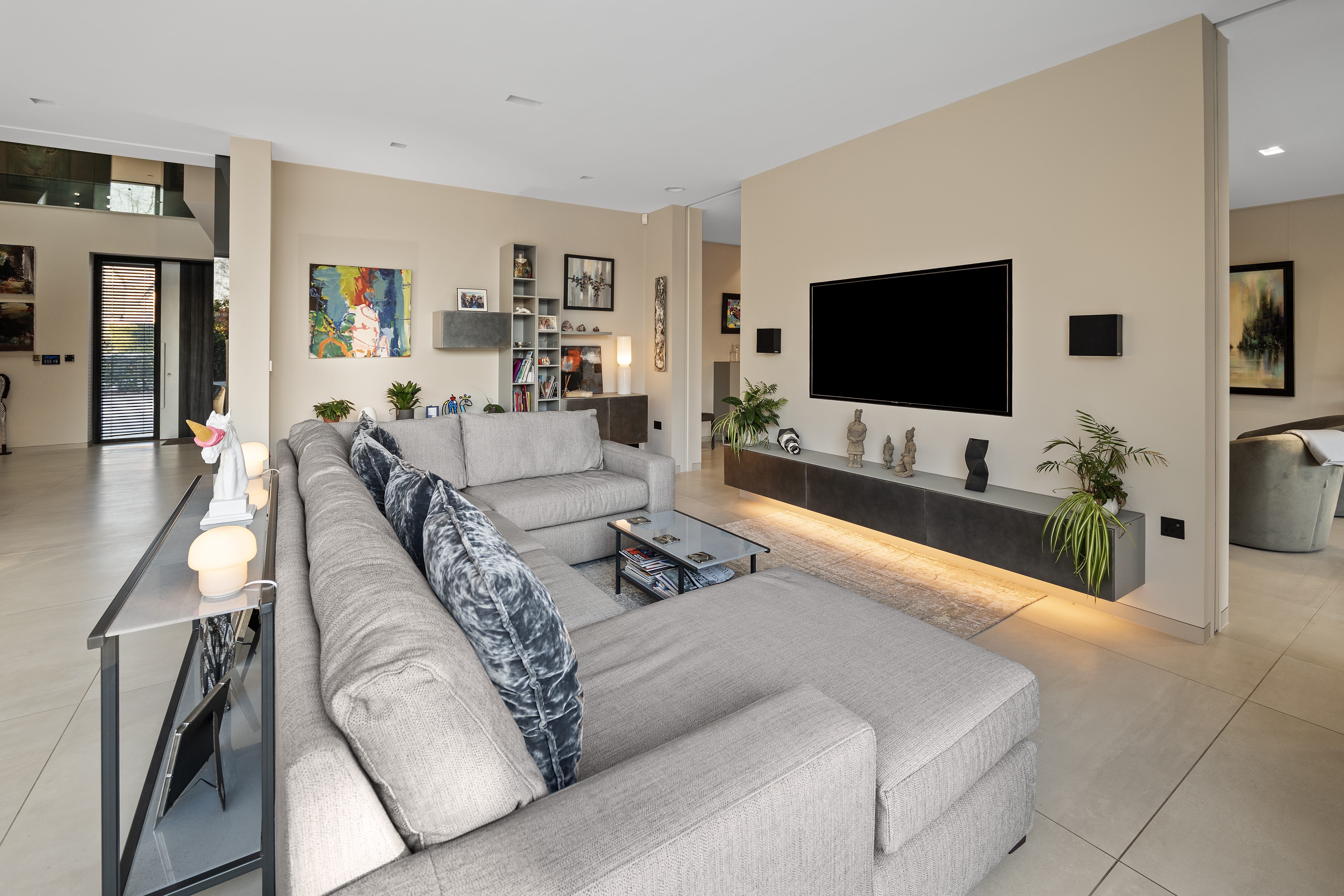 Open-plan living room with sectional sofa and underlit media wall